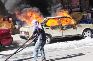 A Kurdish demonstrator stands next to a burning car as Kurdish protesters clash with Turkish police during a rally outlawed by state authoritites to demand the release of jailed rebel leader Abdullah Ocalan , on July 14, 2012, in Diyarbakir (photo: AFP)