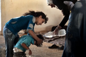 Stranded on the border with Turkey, a Syrian mother takes care of her children after they were displaced from their houses due to fighting between rebel fighters and Syrian government forces on 25 August AFP PHOTO / ARIS MESSINIS