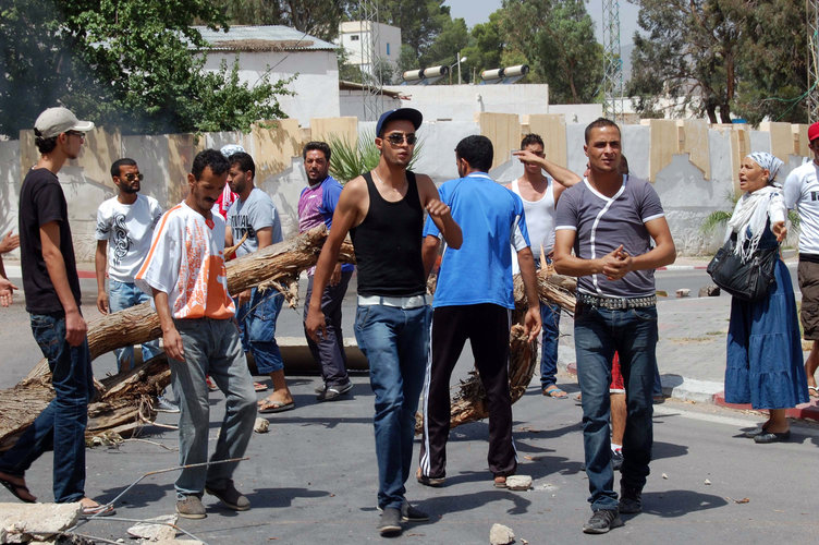 Residents of Kasserine in western Tunisia blocking a road in the centre of the city with a tree during anti-government protests (AFP PHOTO / Abderrazek)