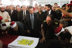 Egyptian Prime Minister Hisham Qandil (C)prepares to lead the prayer over the coffins of the 16 soldiers killed during an attack on a border crossing post in Northern Sinai, during their funeral on August 7, 2012 in Cairo, Egypt-AFP PHOTO/GIANLUIGI GUERCIA