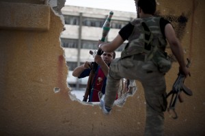 Fighters pass weapons through a hole in a building before an offensive against government forces in Izza neighbourhood of the embattled northern city of Aleppo AFP PHOTO / ZAC BAILLIE