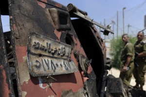 Israeli soldiers inspect a burnt armoured vehicle near the Karm Abu Salem border crossing after gunmen killed 16 Egyptian security officers and crossed into Israel on 6 August AFP PHOTO / DAVID BUIMOVITCH
