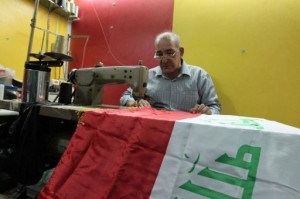 An Iraqi tailor sews a national flag at his workshop in Baghdad AFP Photo / Sabah Arar
