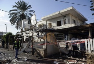 An Israeli policeman inspects damages at a house that was hit by a rocket launched from the Gaza Strip in the southern city of Netivot. (AFP PHOTO / DAVID BUIMOVITCH)