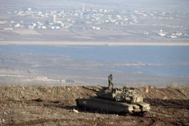 An Israeli soldier stands atop a Merkava tank in the Golan Heights overlooking the Syrian village of Breqa (AFP / FILE PHOTO / Jack Guez)