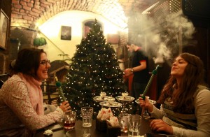 Syrian women smoke shisha as a waiter decorates the Christmas tree at a cafe in the old city of Damascus. The majority of the Christian community in Syria has decided to celebrate Christmas without decorations this year amid the ongoing Syrian conflict but the owner of the cafe decided to carry on with the tradition regardless. AFP Photo / Carole Alfarah