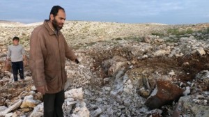 A Syrian man points at a crater where a Scud missile hit in the town of Nasiriyeh on 13 December (AFP / Herve Bar)