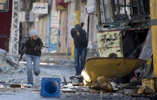 Syrian rebel fighters cross a road targeted by government sniper fire in Aleppo on 8 December (Photo by AFP / Odd Andersen)