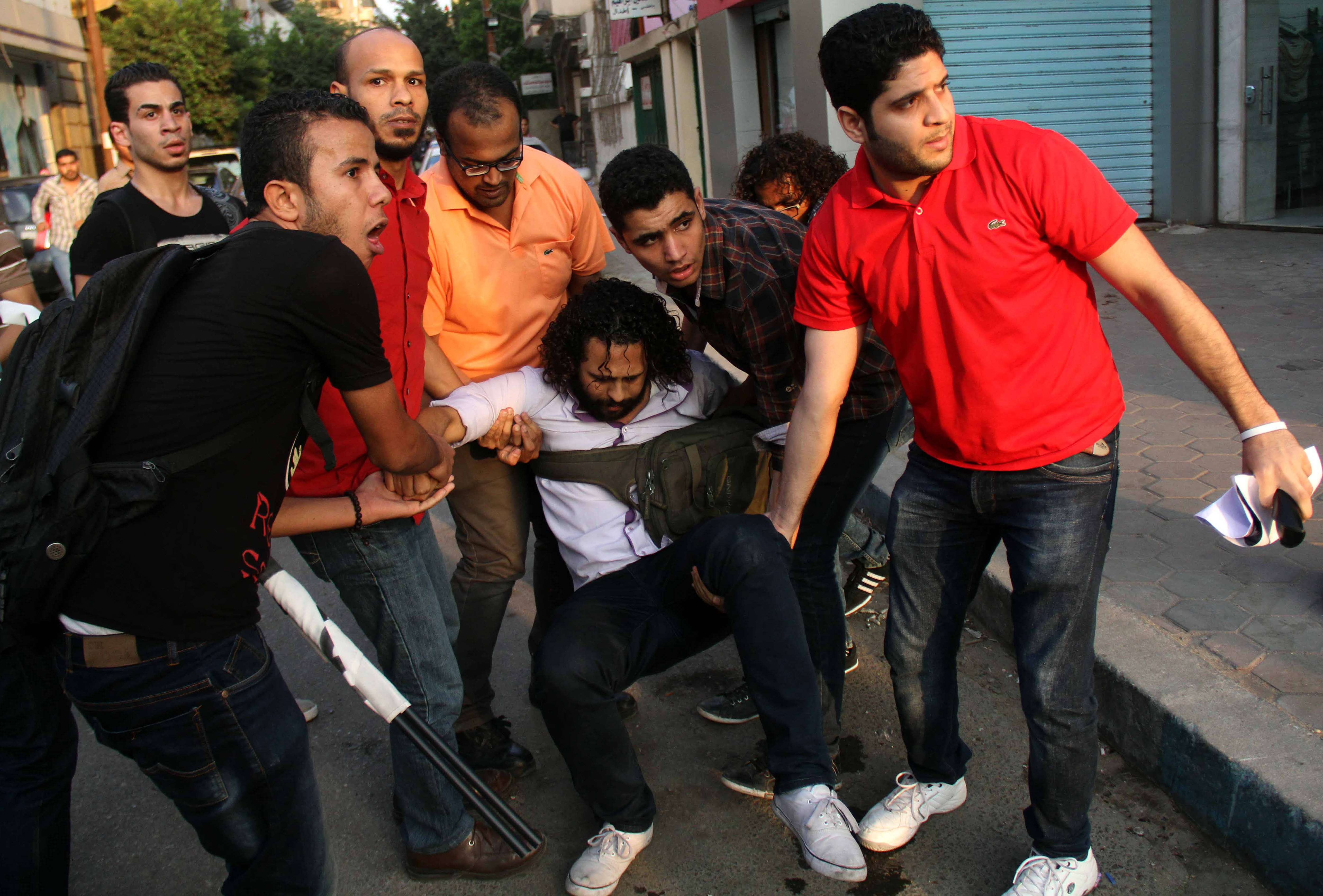Egyptian demonstrators help and injured comrade during clashes with police following a protest against the demonstration law, near the Presidential Palace in Cairo on June 21, 2014. An Egyptian court confirmed death sentences for more than 180 Islamists, including Muslim Brotherhood chief Mohamed Badie, after a mass trial that sparked an international outcry. (AFP PHOTO / AHMED TARANA)