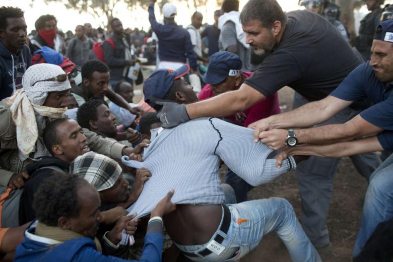 Israeli policemen and immigration officers raid a protest camp set up by African asylum seekers near a border crossing with Egypt in the Negev Desert on June 29, 2014. (AFP Photo/ Oren Ziv)