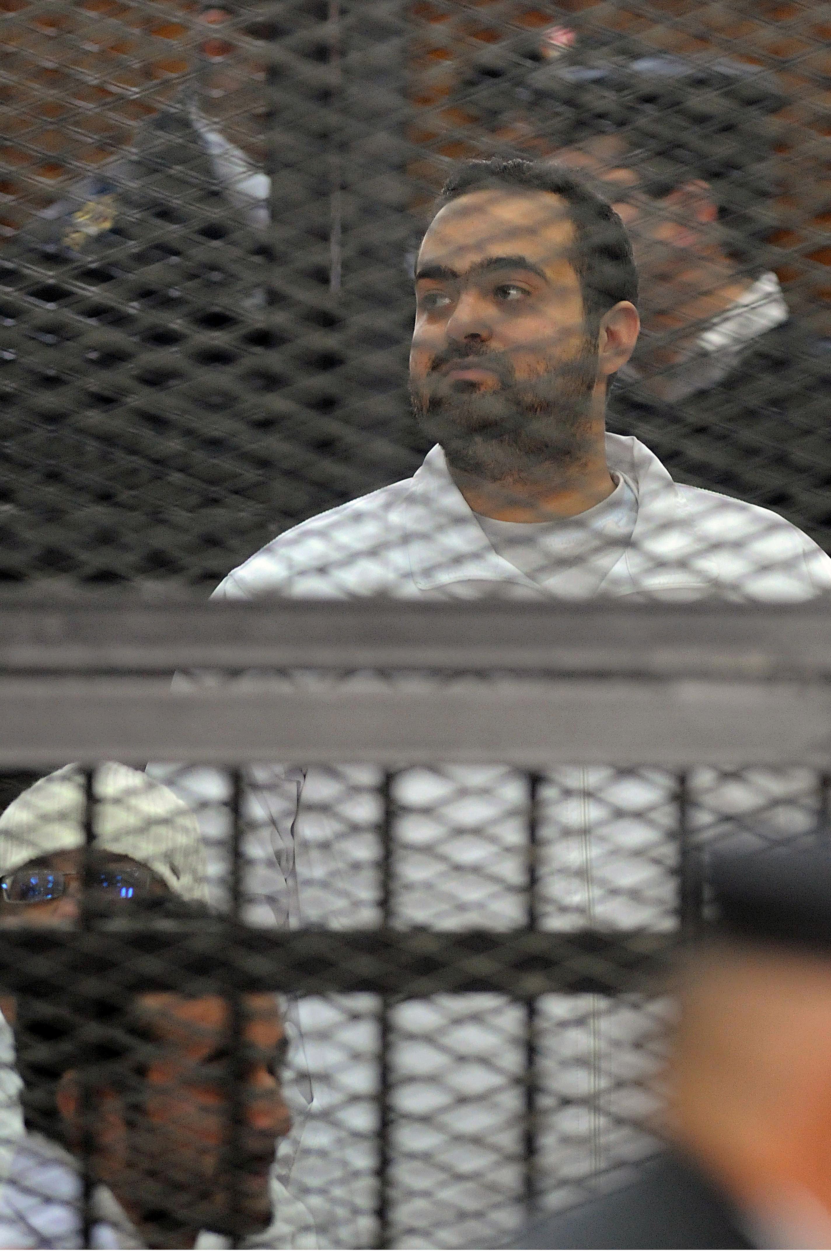 Egyptian prominent activicts Mohamed Adel stands in the accused dock during his trial on December 22, 2013, in Cairo. An Egyptian court sentenced three activists, Mohamed Adel, Ahmed Maher (unseen), the founder of the April 6 youth movement that led the revolt against former president Hosni Mubarak, and Ahmed Douma (unseen), all accused of spearheading the 2011 uprising against Mubarak to three years in jail for organising an unlicensed protest, judicial sources said. It was the first such verdict against non-Islamist protesters since the overthrow of president Mohamed Morsi in July, and was seen by rights groups as part of a widening crackdown on demonstrations by military-installed authorities. (AFP PHOTO/STR)