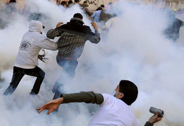 An Egyptian protester prepares to hurl a tear gas canister back at security forces as others run for cover on the third day of the 2011 Mohamed Mahmoud clashes near Tahrir Square in Cairo (AFP/ file photo)