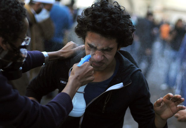 An Egyptian protester sprays water on the eyes of a fellow demonstrator after tear gas was fired by security forces in November 2011. (AFP/ file photo)