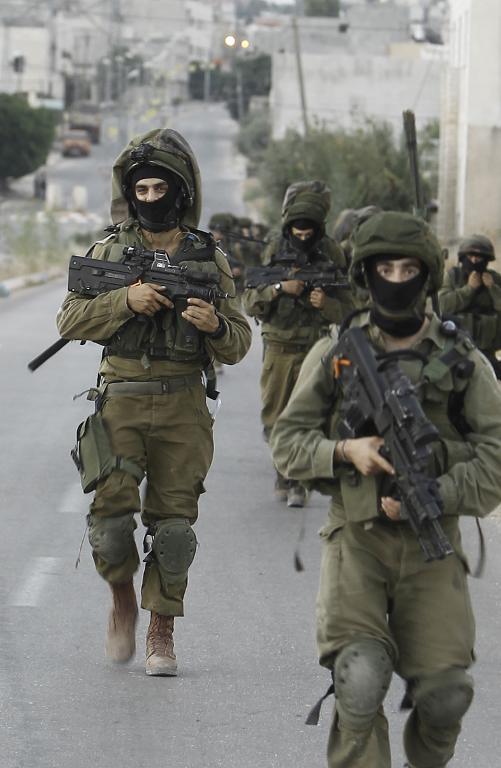 Israeli soldiers patrol a street in the West Bank village of Beit Furik, southeast of Nablus, early on June 20, 2014, as they take part in a search for three teenagers believed kidnapped by Hamas