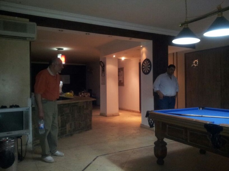 Dr Ahmed Dawoud and Am Atef at billiard table watching rehab centre residents playing a game (Photo By Ethar Shalaby)