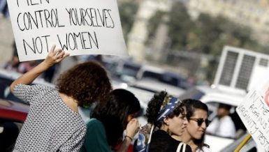 Female protester against sexual abuse carrying a sign saying men control yourselves not women