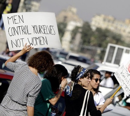 Female protester against sexual abuse carrying a sign saying men control yourselves not women