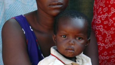 Photo taken on July 11, 2005 shows a South African mother and her child waiting for food distribution in a slum near Pretoria, South Africa. (Xinhua)