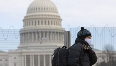 A man wearing a face mask walks past the U.S. Capitol building in Washington, D.C., the United States, Jan. 24, 2021. Amid surge in US COVID-19 cases (Photo by Aaron Schwartz/Xinhua)