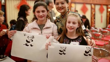 Two girls show their paintings of panda with Chinese traditional painting artist Zhang Liping (C) during the event "From China to Chicago: A Holiday Gathering & Celebration" in Chicago, the United States, on Dec.14, 2019. (Xinhua/Wang Ping)